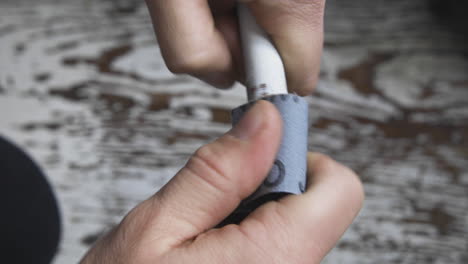 a man fits sandpaper around an old copper pipe and starts twisting it