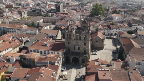 Movimiento-De-Paralaje-Aéreo-Antigua-Catedral-De-Piedra,-Rodeada-De-Tejados-Rojos---Centro-De-La-Ciudad-De-Braga