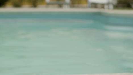 little boy in watersport goggles diving in water in swimming pool and looking at the camera