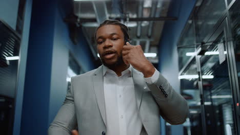 Focused-afro-man-speaking-on-phone-in-office.-Man-using-smartphone-in-corridor