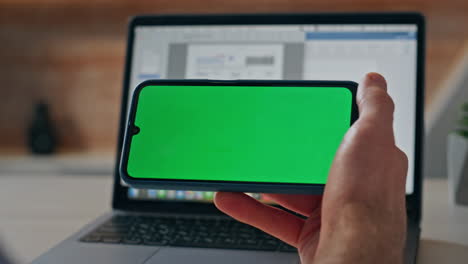 man touching chroma key mobile phone in horizontal position at workplace closeup