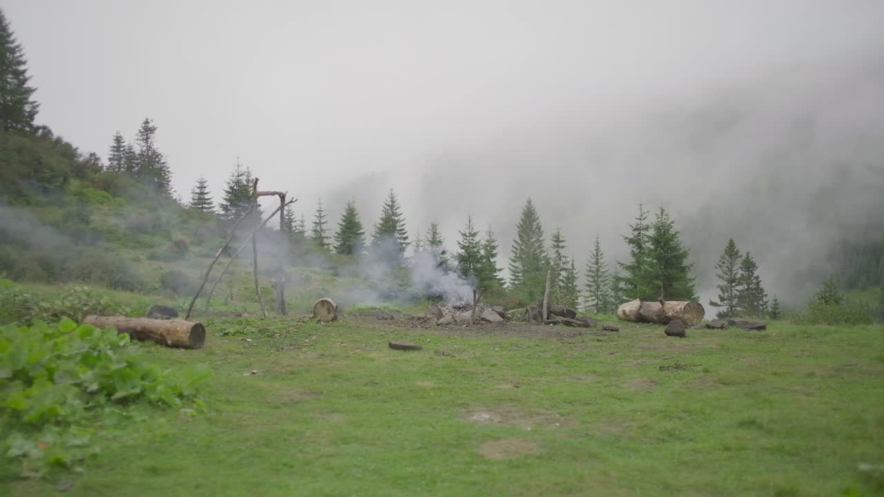 Bjergcampingplads med brændende bål og røg. Bjerglandskab uden mennesker