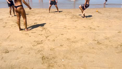 Weite-Sicht-Auf-Eine-Fitte-Frau,-Die-In-Zeitlupe-Am-Strand-Volleyball-Spielt,-Junge-Leute-Spielen-Im-Sommer-Am-Strand-Ball,-Amateurmannschaftstraining