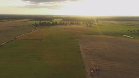 aerial heavy agricultural machinery tractors with implements in agricultural fields on a sunny summer evening