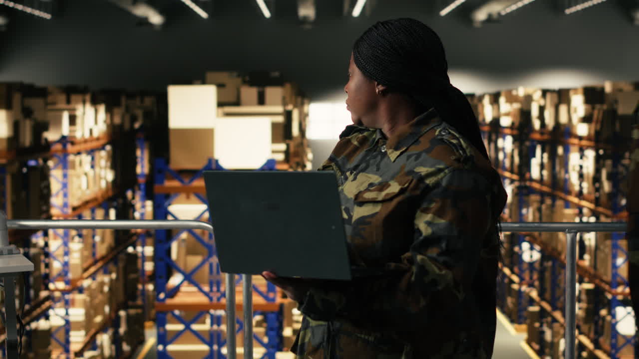 African American Woman in Camouflage Uniform Working on Laptop in Warehouse
