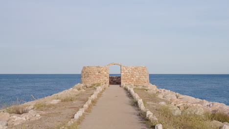 wide shot of a ruined fortification located on the coast with blue sea views and clear skies