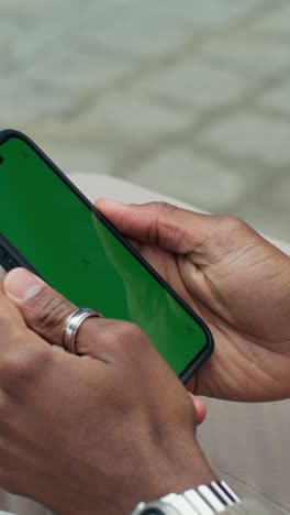 person holding smartphone with green screen