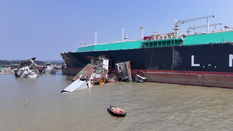 cinematic aerial drone shot of a wreckage near a cargo ship in a ship graveyard in bangladesh
