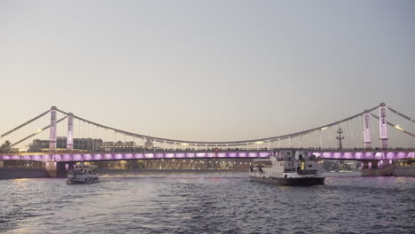 evening view of a cable-stayed bridge over a river with boats in st. petersburg, russia