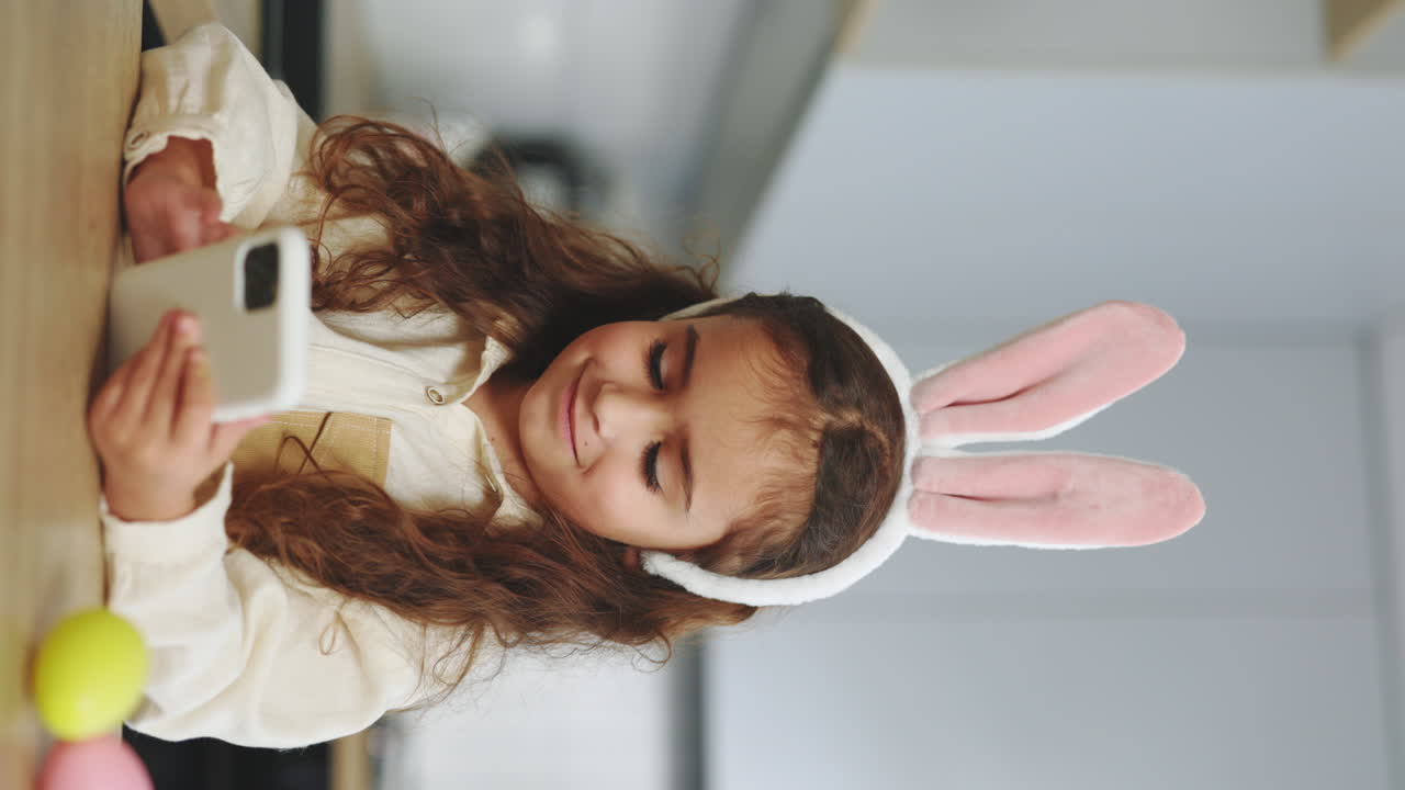 Child Using Phone with Bunny Ears in Kitchen
