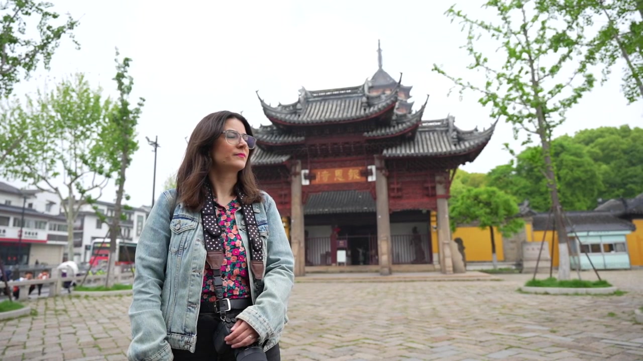 Giovane donna caucasica con una macchina fotografica che esplora un tempio buddista storico a Suzhou, Cina.