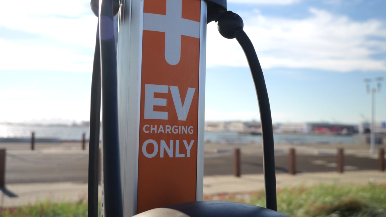 Otoparktaki elektrikli araçlar için bir EV şarj istasyonunun yakın çekimi; sürdürülebilir ulaşımı ve sıfır karbon emisyonlu, yenilenebilir yeşil enerjinin geleceğini temsil ediyor.