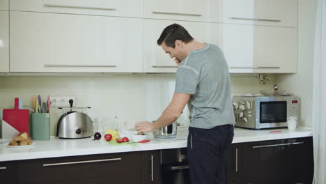 hombre sonriente cocinando una cena saludable en una cocina moderna.