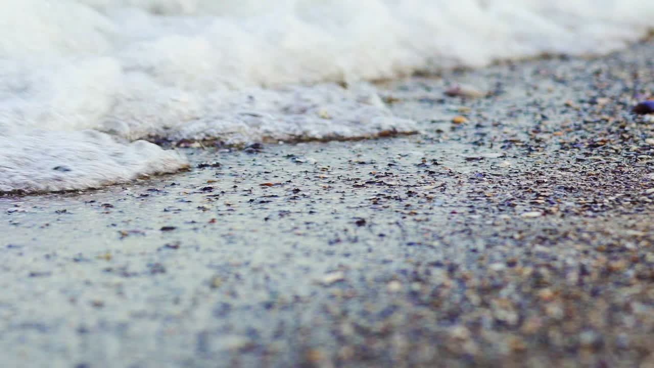 Foamy sea shore at the beach. Close up view of soft waves lapped the sandy beach