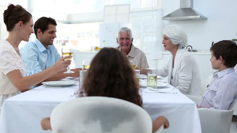 Family-sitting-at-dinner-table-and-toasting