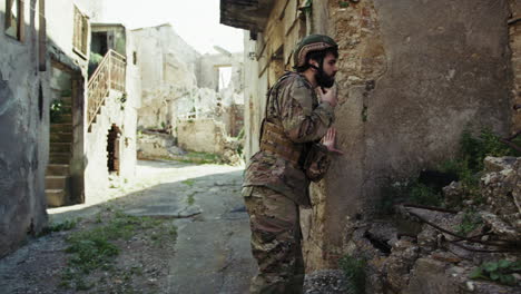 soldier looks for something among the ruins of the destroyed city by war