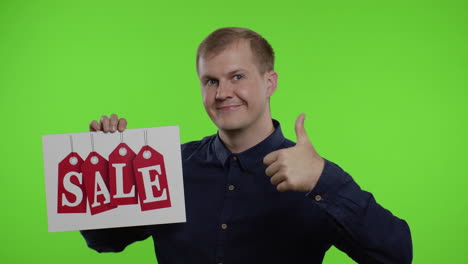 happy man holding sale word inscription and showing thumb up. guy rejoicing with good sale discounts