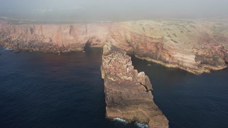 orbitando disparado sobre la formación rocosa en la costa sureste de portugal, enorme acantilado por el océano atlántico