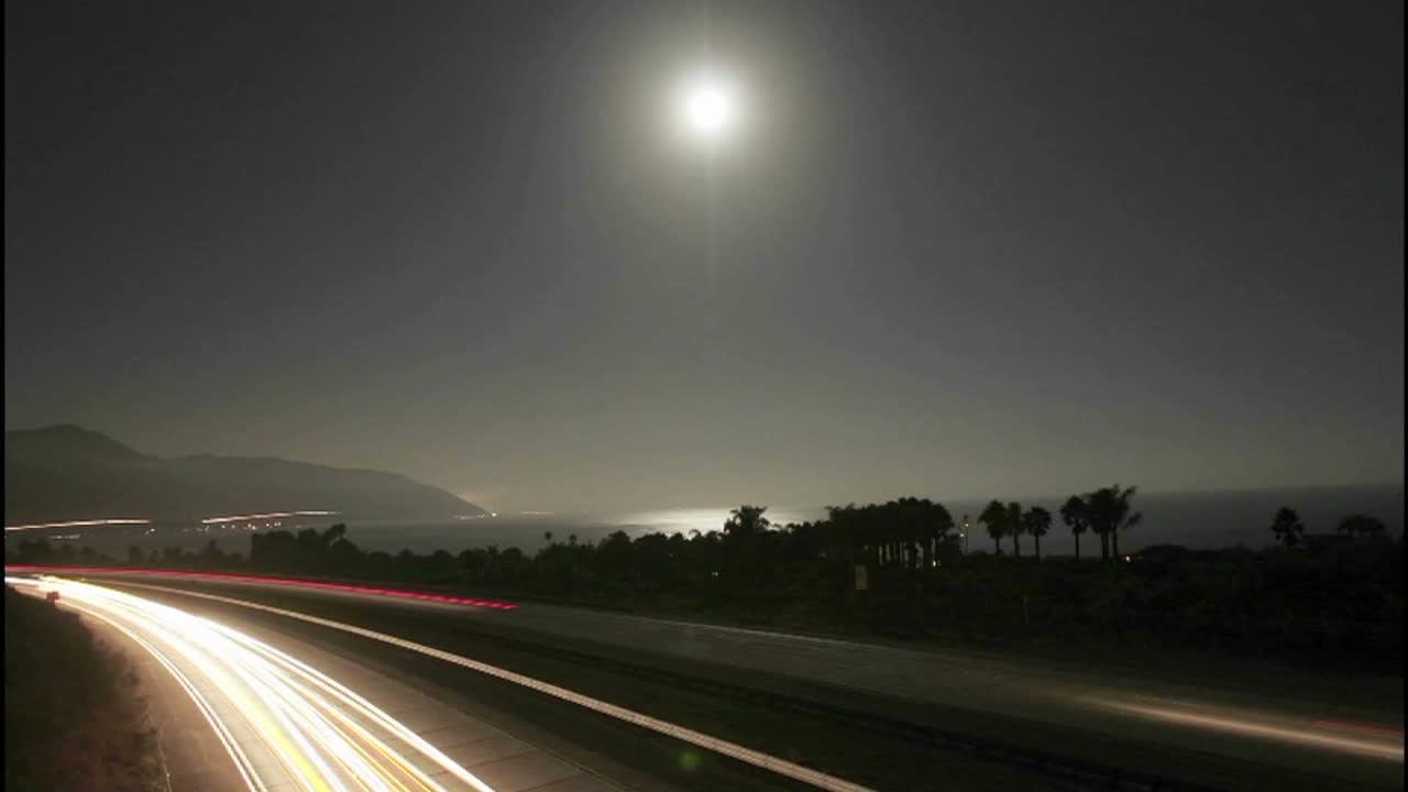 밤에 해변 근처의 달과 교통의 시간 경과