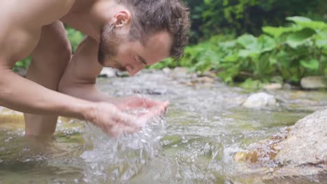 man washing his face in stream water. slow motion.