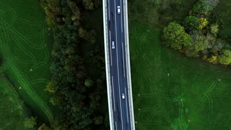 vista aérea con un dron sobre una carretera en francia. sólo campos de hierba y árboles alrededor de las carreteras. coches y camiones conduciendo en las carreteras bajo el sol.