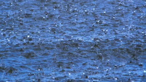 Großer-Regen-Auf-Der-Wasseroberfläche,-Das-Wasser-Ist-Blau,-Die-Tropfen-Plätschern