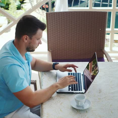 Man-With-Coffee-Cup-Uses-A-Laptop