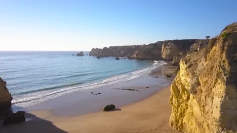 aerial or a drone shot over some mountains and cliffs in portugal while the sun is shining during the day time