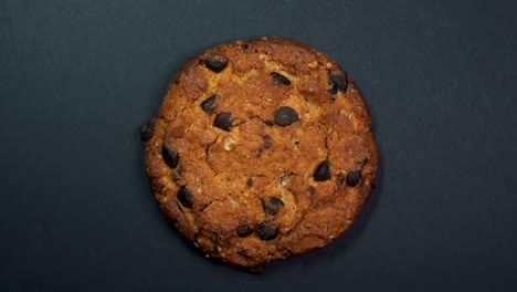 una galleta de chocolate en primer plano, una foto macro, girando lentamente sobre un fondo negro giratorio.
