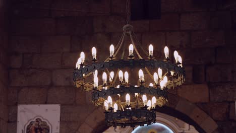 medieval-style chandelier with lit candles in an old stone chamber