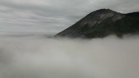 the wonderful chic-choc mountains revealed behind the thick fog in gaspe peninsula, quebec, canada - aerial drone