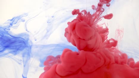 tanque de agua del acuario con un poco de tinta azul, más tinta roja rociada desde la jeringa - fondo abstracto