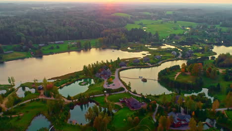 Vista-De-Pájaro-Sobre-Un-Paisaje-Verde-Con-Bosques-Y-Lagos-Con-Casas-De-Campo-En-El-Medio