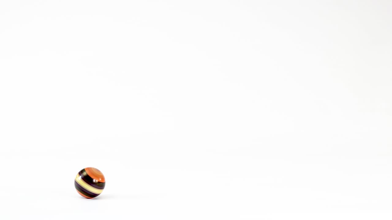 A brown striped wooden bead bounces and spins across a clean white studio background