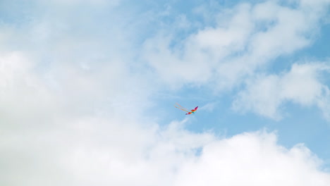 colorful kite soaring in a cloudy blue sky