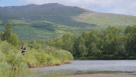 man fishing among beautiful lapland landscape in summer, sweden