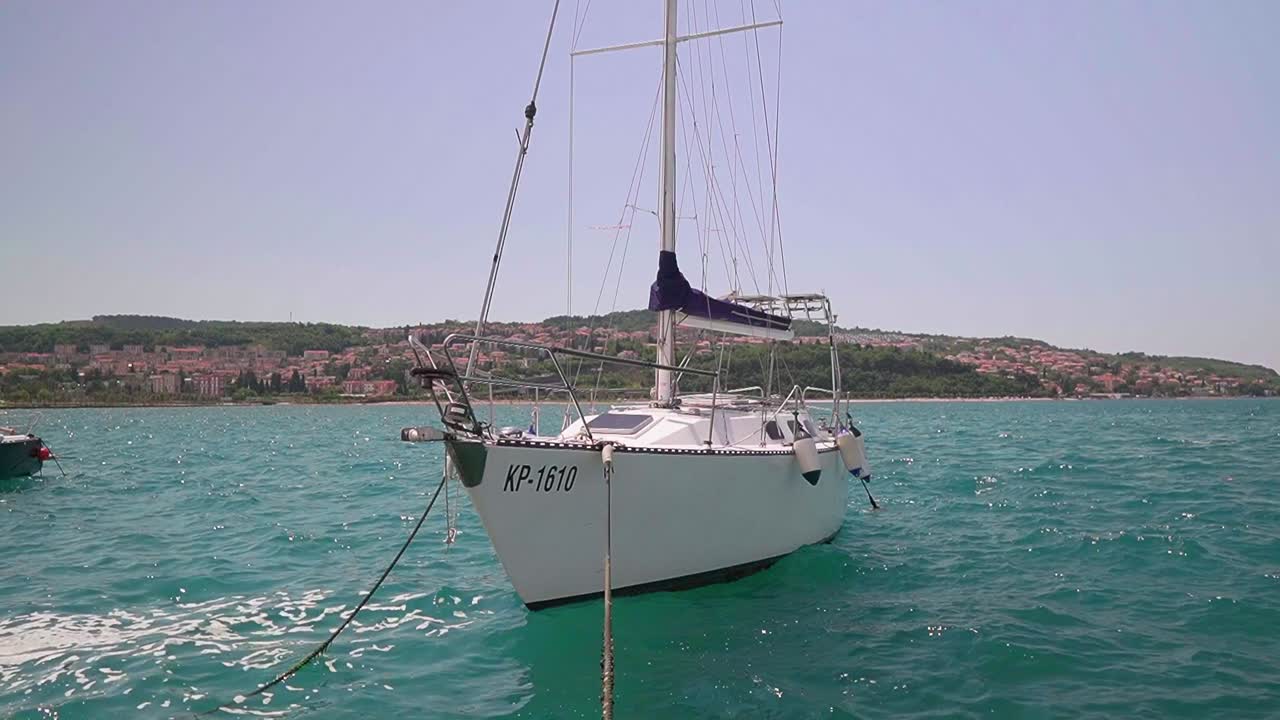 Stunning HD footage captures a sailboat gently swaying in Koper's marina, amid the waves of the Adriatic Sea
