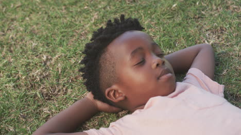 lying on grass, african american boy relaxing with eyes closed, enjoying peaceful moment