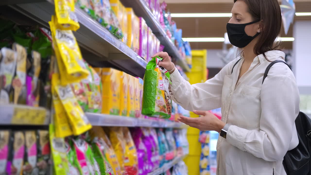 한 여자 가 식료품 가게 에서 반려동물 음식 을 구입 하고 있다