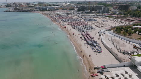 Imágenes-Aéreas-Sobre-Las-Olas-En-La-Playa-De-Resorts-En-Bari,-Italia-Durante-El-Día