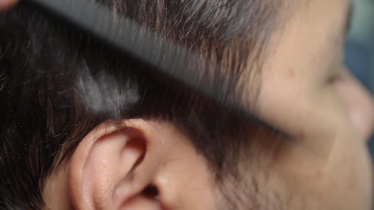 Close-up of a man's face during hair removal with tweezers
