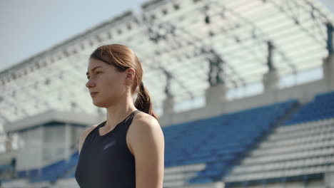 beautiful woman athlete at the stadium breathing and preparing to start the race. motivation and tuning for the race. concentration and attitude