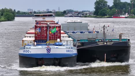 two cargo ships, including a container vessel, navigating a river