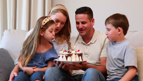 Feliz-Familia-Joven-Sentada-En-El-Sofá-Celebrando-Un-Cumpleaños-