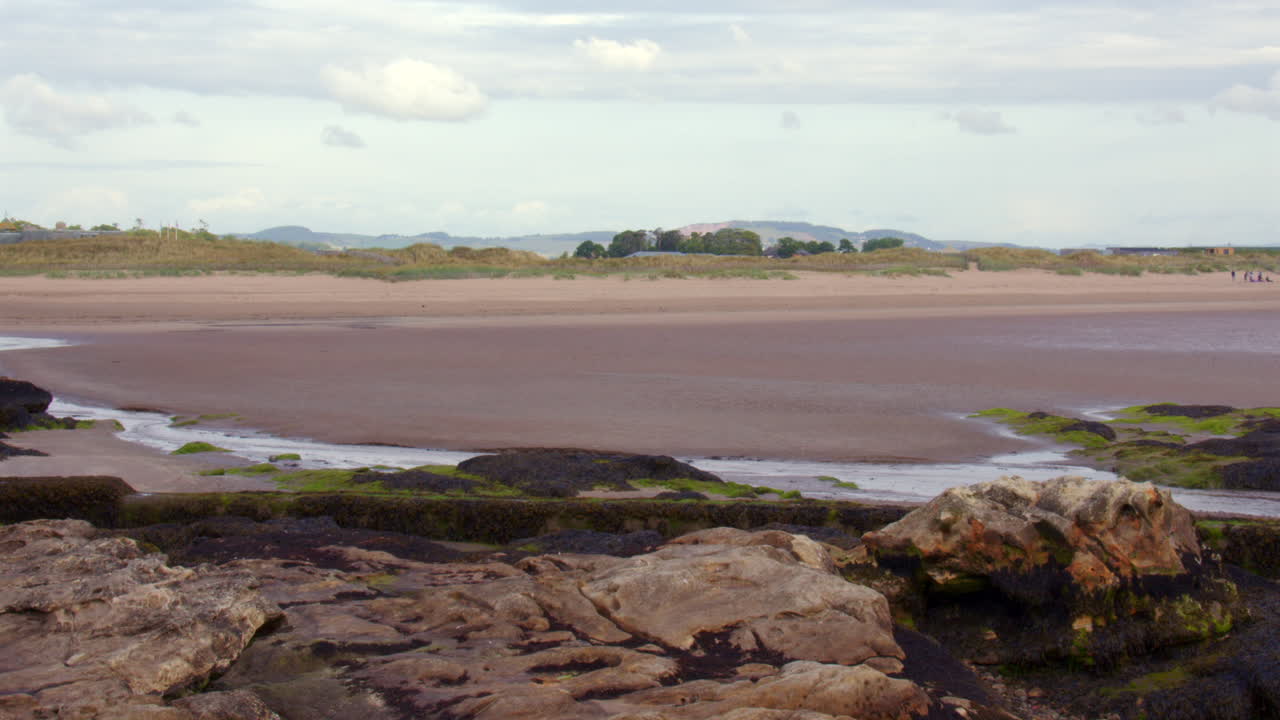 Wide shot looking north up west sands beach at St Andrews with Exposed rocks at low tide