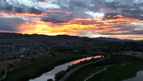 Puesta-De-Sol-Dorada-Sobre-Un-Campo-De-Golf-Reflejándose-En-Un-Río---Panorama-Aéreo