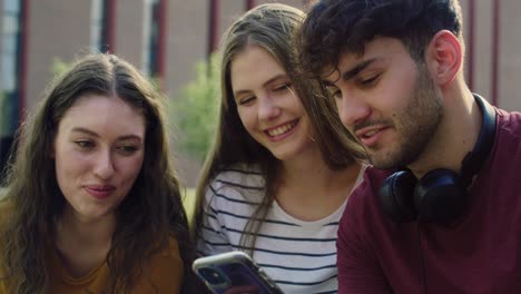 grupo de estudiantes navegando por teléfono junto al campus universitario