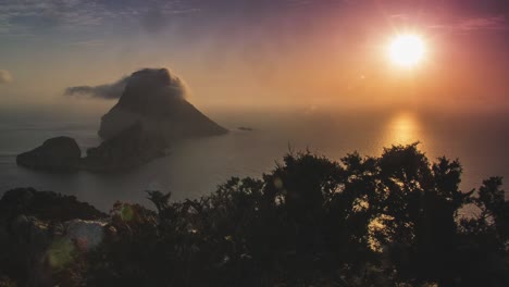 stunning 4k time-lapse of sunset at es vedra ibiza in spain with moving clouds in the mountains