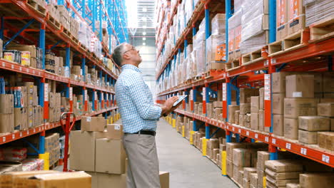 Warehouse-worker-using-digital-tablet-while-checking-packages