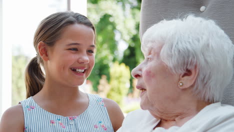 Granddaughter-Sitting-And-Talking-With-Grandmother-During-Visit-To-Retirement-Home